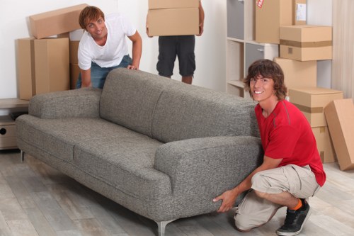 Professional movers carrying items through a Queens Park apartment building